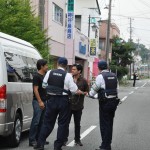 福島第一原発から約５㌔離れた大熊町の商店街にて。県外からも警察官がパトロールに訪れている。巡回中の警察官にインタビューをする大学院生ら/2016年５月24日