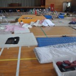 帰還困難地区の中学校体育館。２０１１年３月14日原発事故後の第一次避難所となった場所。当時の被災者の寝袋、靴、新聞などそのまま放置されている。２０１６年5月２５日